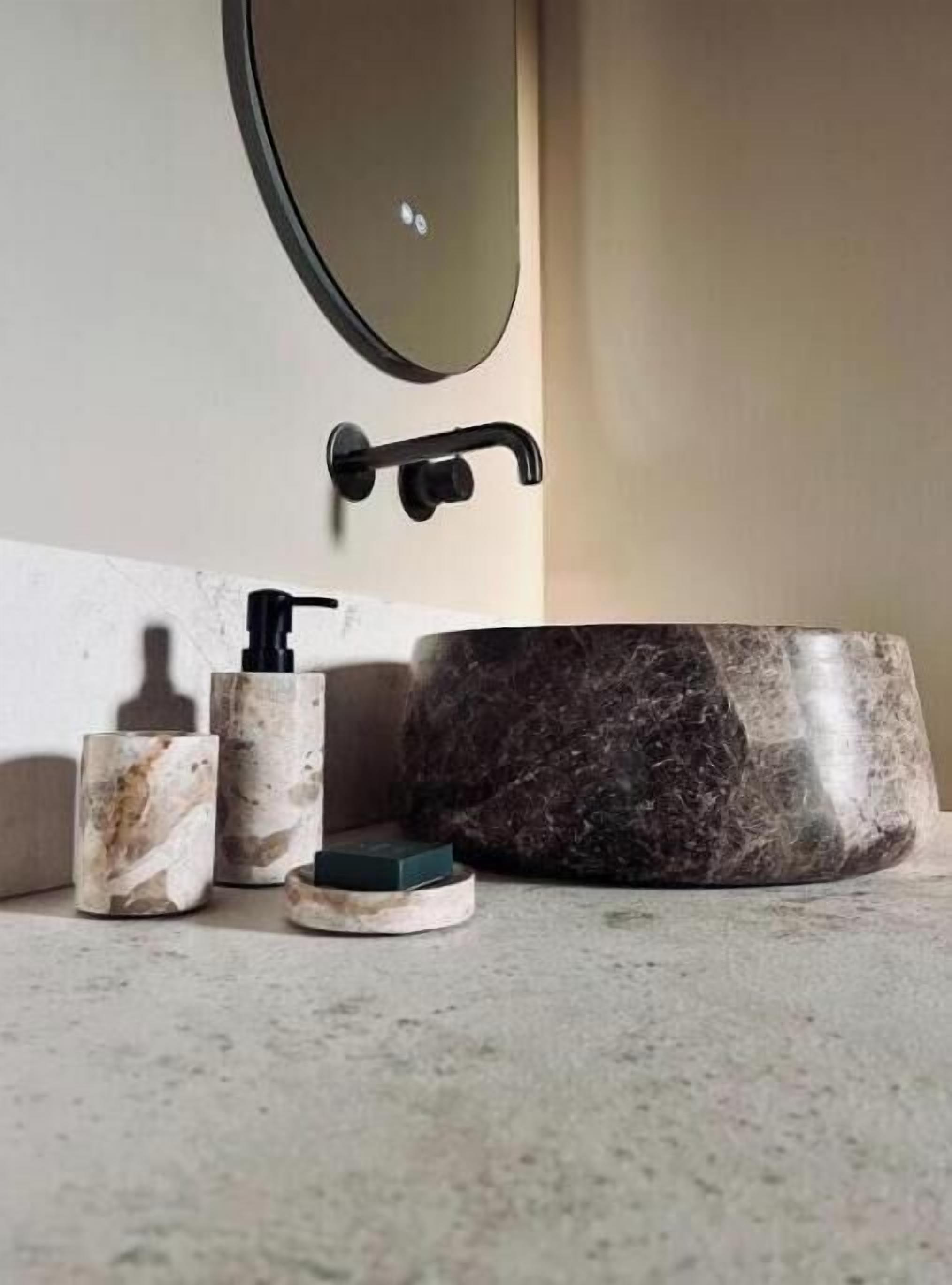 A bathroom with a marble sink, a soap dispenser, and a soap dish.