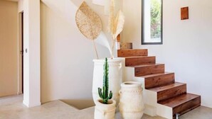 Eine Treppe mit Holzdielen, eine weiße Vase mit einem Kaktus und eine hohe Vase mit getrockneten Pflanzen.