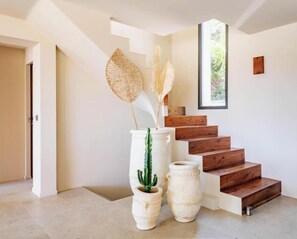 A staircase with wooden steps, a white vase with a cactus, and a tall vase with dried plants. - Villa LoKa - 5 bedrooms, swimming pool - Gulf of Saint-Tropez (Grimaud)