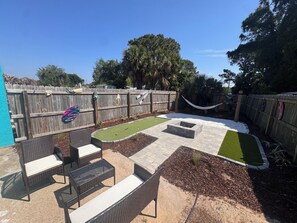 Ein Garten mit Terrasse, kleinem Rasen und Holzzaun.