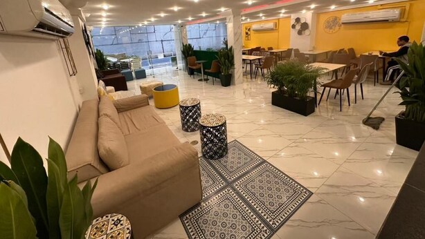 A spacious hotel lobby with a sofa, dining area, and potted plants. - Siam Boutique Hotel (Phayathai Road Bangkok)