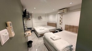 A hotel room with two beds, a small bedside table, a wall-mounted air conditioner, a mirror, and a trash bin. - Siam Boutique Hotel (Phayathai Road Bangkok)