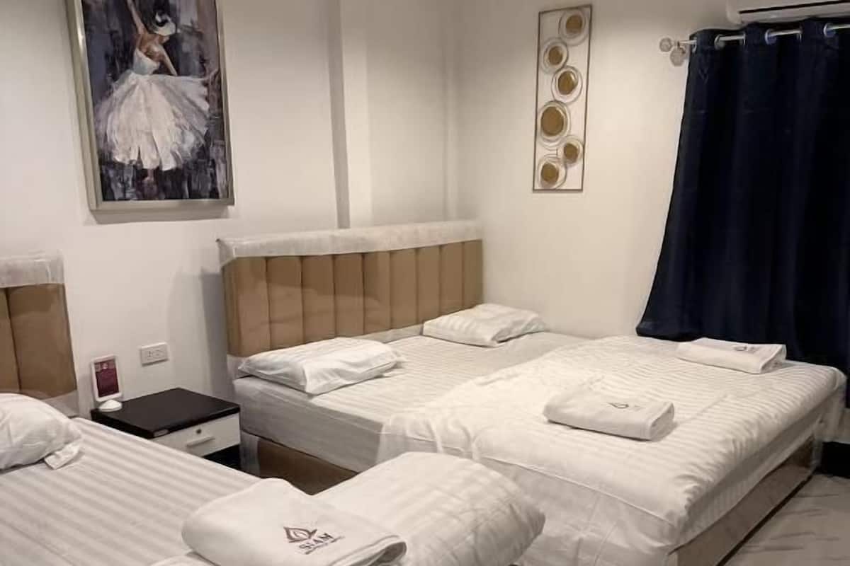 Una habitación de hotel con dos camas, una mesita de noche, un cuadro y una lámpara en el techo.