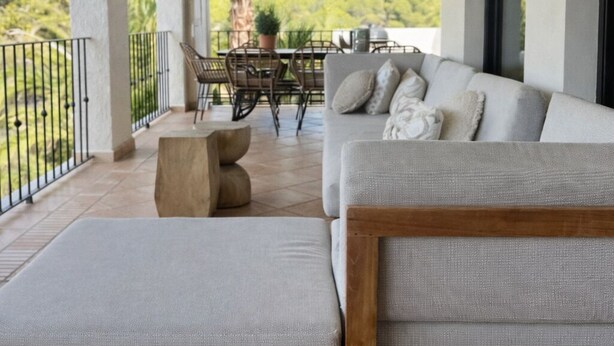 A covered outdoor seating area with a sofa and ottoman, a table, chairs, and hanging wicker lamps. - Casa Voskamp your dream vacation with sea view near beach & center in Moraira! (Teulada)