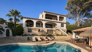A two-story house with a swimming pool, outdoor seating, and a stone wall. - Casa Voskamp your dream vacation with sea view near beach & center in Moraira! (Teulada)