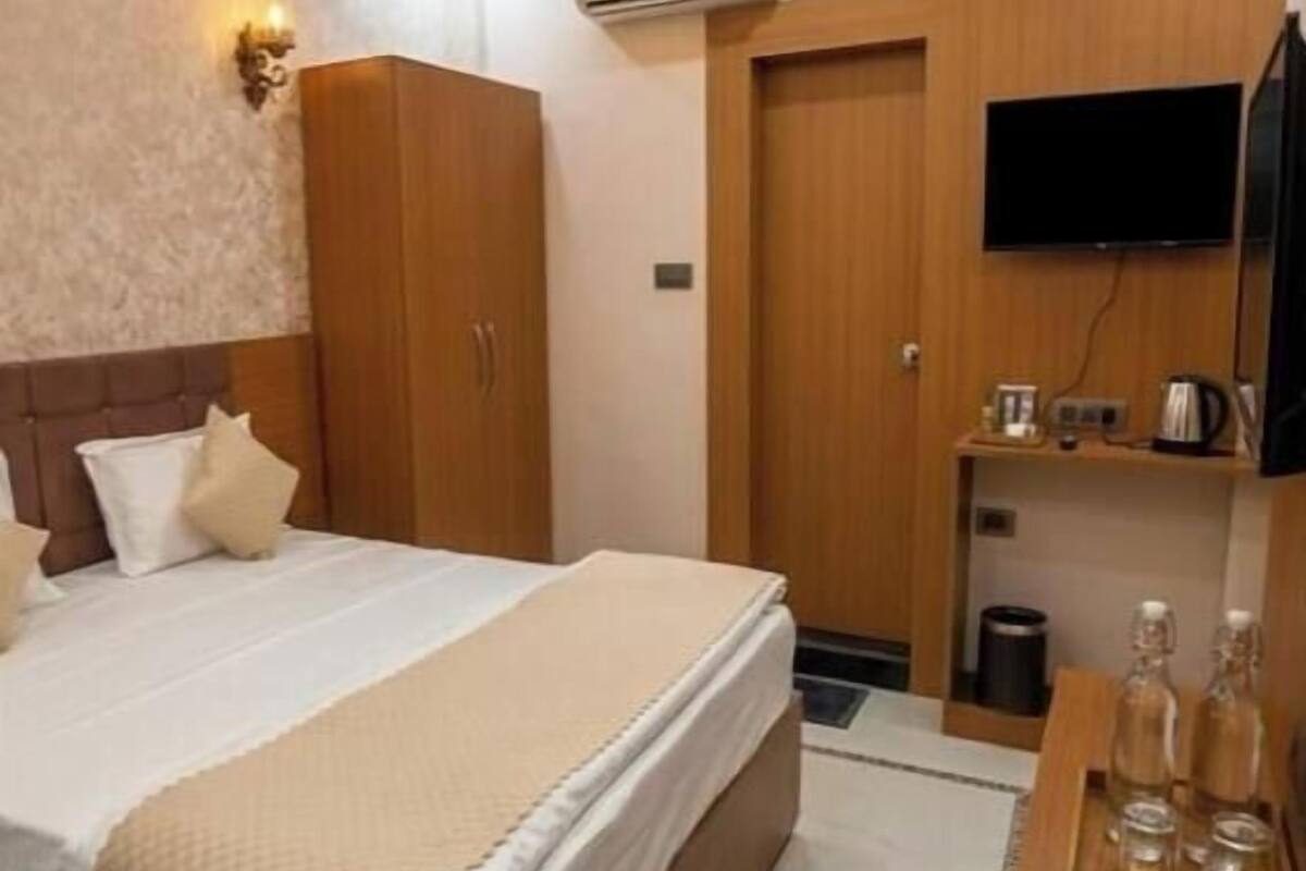 Un dormitorio con cama, armario, televisor y una mesita con botellas.