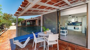 Eine Terrasse mit Tisch, Stühlen und einem blauen Sofa.