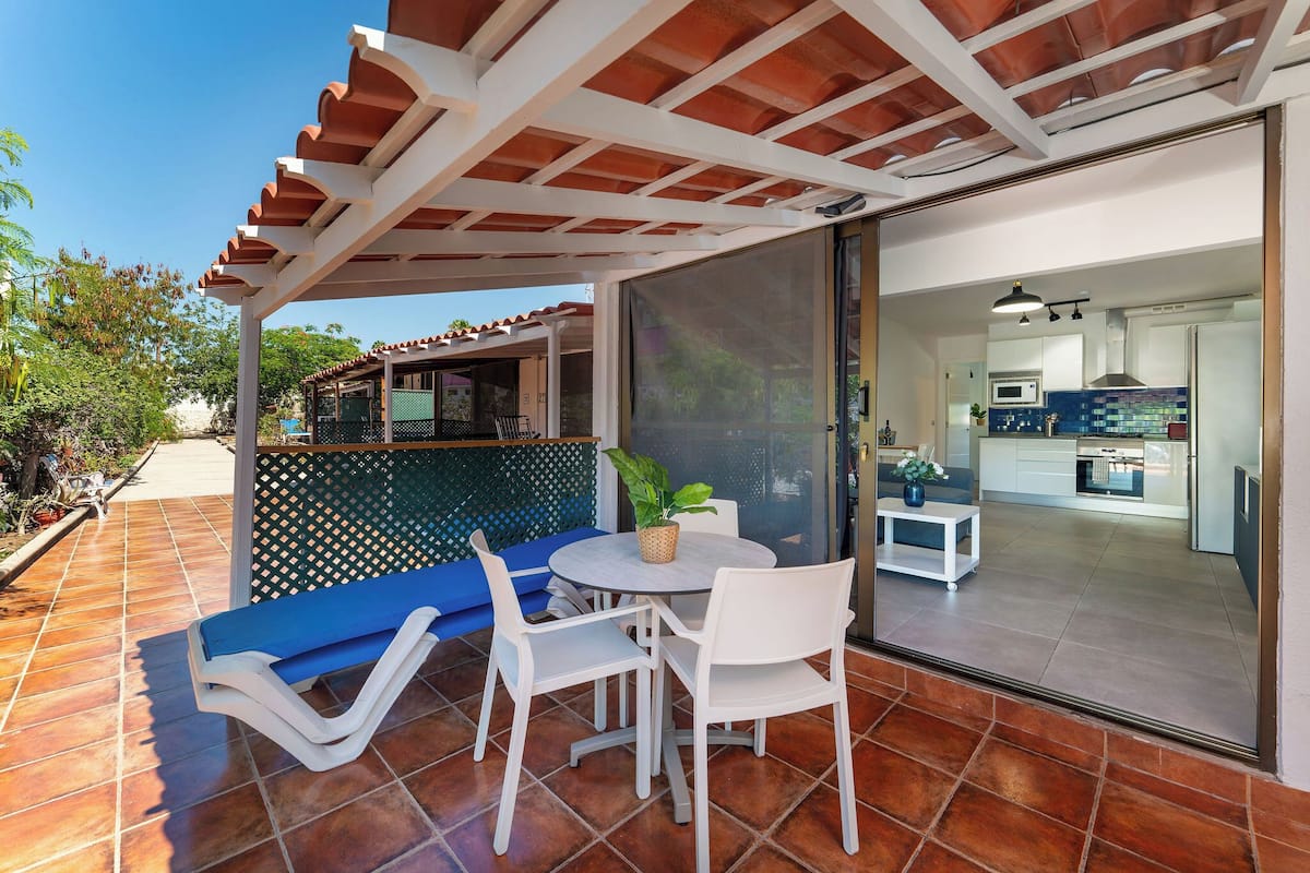A patio with a table, chairs, and a blue sofa.