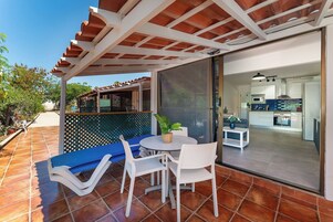 Une terrasse avec une table, des chaises et un canapé bleu.