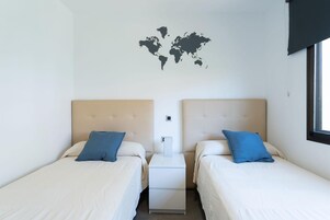 A hotel room with two beds, a world map on the wall, and a window.