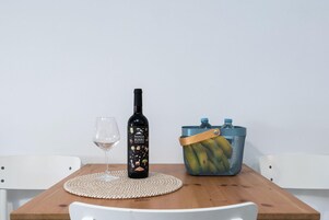 A bottle of Panza Burro wine, a glass, and a mesh bag with water bottles on a wooden table.