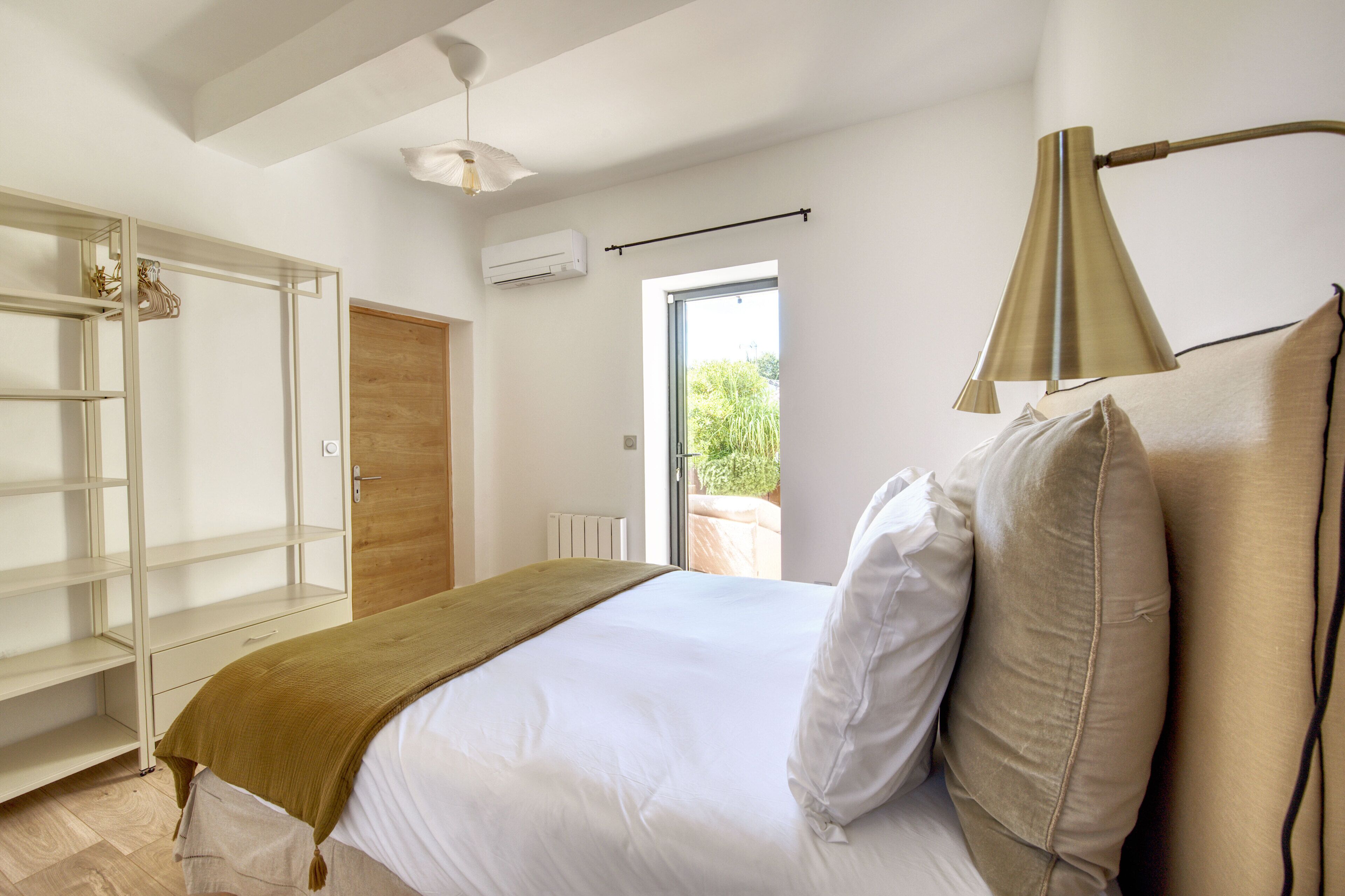 Een slaapkamer met een bed, een kledingkast, een raam en een plafondventilator.