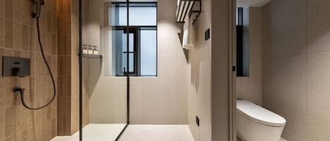 A modern bathroom with a glass shower enclosure, a toilet, and a window providing natural light.