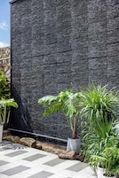 A modern outdoor area with a textured wall, potted plants, and a tiled floor.