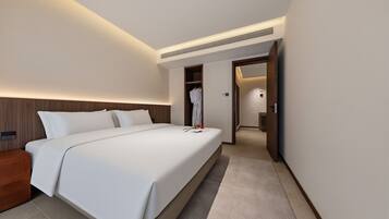 Una habitación de hotel moderna con una cama grande, un vestidor y un baño visible a través de una puerta abierta.