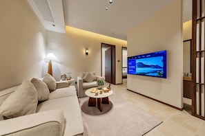 A modern living room with a sofa, armchairs, a coffee table, and a flat-screen TV mounted on the wall. - APOLLO COURTYARD HOTEL (Zhangjiajie)