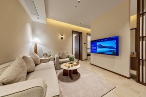 Una sala de estar moderna con un sofá, sillones, una mesa de centro y un televisor de pantalla plana montado en la pared.