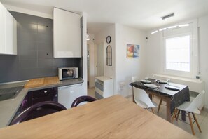 A modern kitchen with a microwave, a wooden cutting board, and a dining area with a table and chairs. - WELCS APARTMENT 351 EMP with terrace (Rosas / Roses)