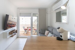 A modern living room with a sofa, a coffee machine, a TV, and a sliding glass door leading to an outdoor area. - WELCS APARTMENT 351 EMP with terrace (Rosas / Roses)