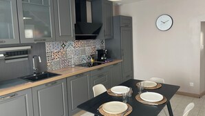 A modern kitchen with grey cabinets, a black countertop, and a tiled backsplash. - 4 P. house in a charming Breton village (Pont-Aven)