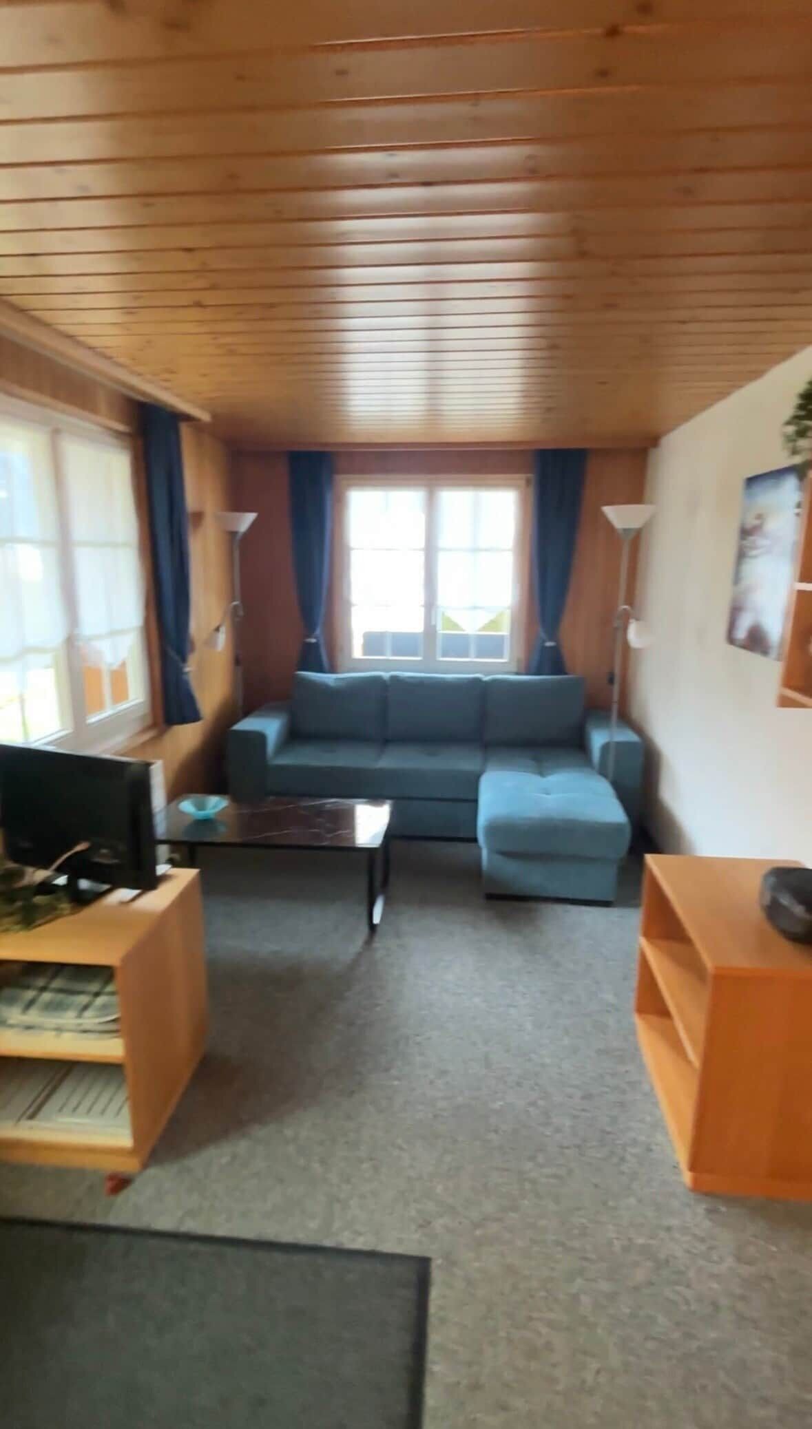 A cozy living room with a sofa, a coffee table, and a TV.