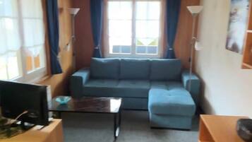 A cozy living room with a sofa, a coffee table, and a TV.