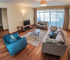 A modern living room with a sofa, armchair, TV, and coffee table. - 3B Apt at Valley Arcade by Karibu Stays (Nairobi)