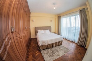 Una camera da letto con un letto, un'armadio in legno e vista attraverso una finestra con tende.