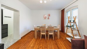 Un comedor con una mesa y sillas de madera, una lámpara de techo y un ventanal con cortinas.