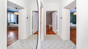 Un pasillo con un suelo de diseño geométrico que lleva a una habitación con cama y mesa.