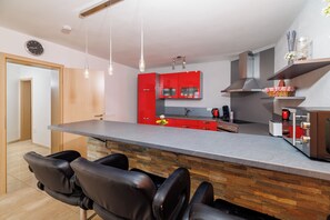 A modern kitchen with a central island, red cabinets, and a built-in stove. - Studio in Crikvenica with pool, sea view & parking space (Crikvenica)