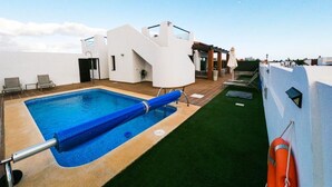Una piscina en la azotea con una cubierta azul, un flotador salvavidas y cielo despejado.