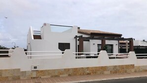 Un edificio moderno con fachada blanca, un patio cubierto y una calle en su frente.