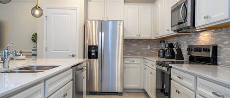 A modern kitchen with white cabinets, stainless steel appliances, and a tiled backsplash.