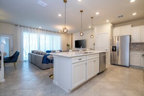A modern kitchen with a central island, stainless steel appliances, and pendant lighting. - New Home w/ Exclusive Décor, Private Pool, BBQ & Windsor Cay Resort Access! (Clermont)