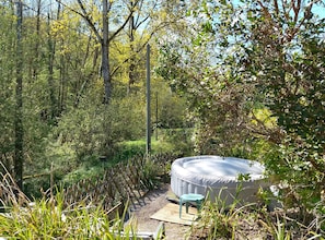 Un bain à remous situé dans un espace boisé, avec une terrasse en bois et une petite table.