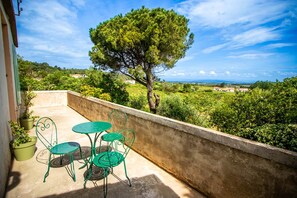Un balcon avec une table et des chaises, un arbre et une vue sur la campagne.