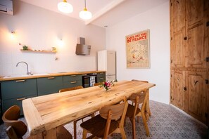 Une cuisine avec une table en bois, des chaises, un évier et une affiche accrochée au mur.