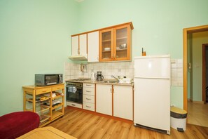 A compact kitchen with wooden cabinets, a microwave, a sink, and a refrigerator. - Apartment with balcony and parking space for up to 4 people (Crikvenica)