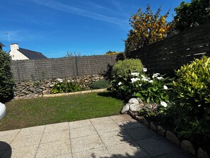 A garden with a stone wall, a wooden fence, and various plants. - South-facing house with all modern conveniences in a quiet location with parking and garage. (Quiberon)