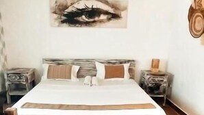 Ein Schlafzimmer mit einem Bett, einem Holz-Kopfteil, einem Wandbild, einem Nachttisch und einem Teppich.