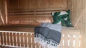 A wooden sauna with a bench, a wall-mounted thermometer, and a patterned blanket. - Hemsedal apartment with 3 bedrooms, 2 bathrooms and sauna (Buskerud)