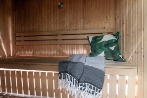 A wooden sauna with a bench, a wall-mounted thermometer, and a patterned blanket. - Hemsedal apartment with 3 bedrooms, 2 bathrooms and sauna (Buskerud)