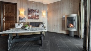 A cozy room with a wooden wall panel, a fireplace, a sofa with cushions, and a table with decorative items. - Hemsedal apartment with 3 bedrooms, 2 bathrooms and sauna (Buskerud)
