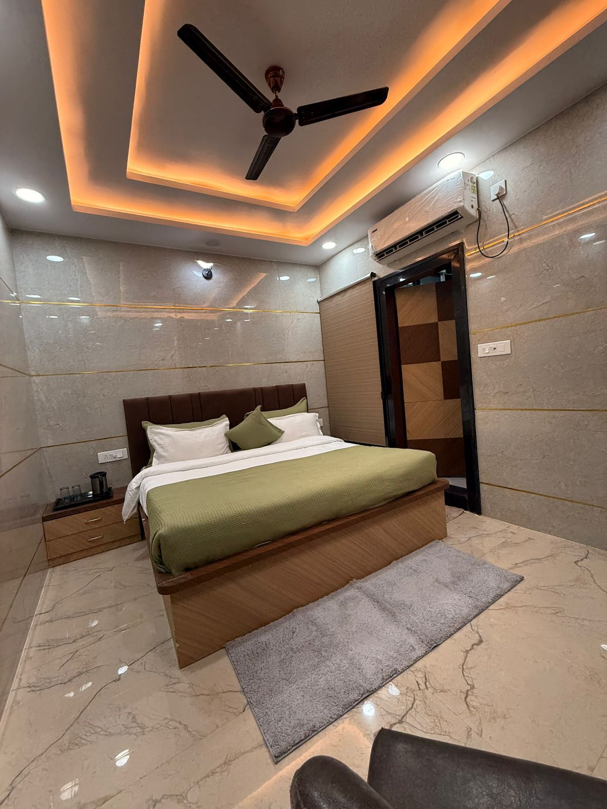 A modern bedroom with a bed, a ceiling fan, and an air conditioning unit.