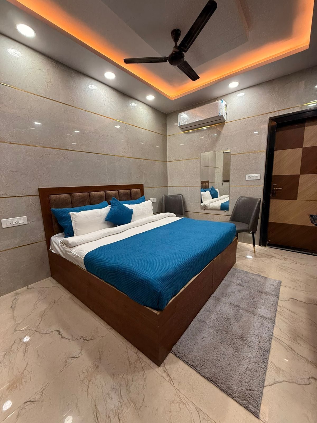 A modern bedroom with a large bed, a ceiling fan, and a mirror.
