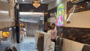 A reception area with a marble counter, leather chairs, and a chandelier. - Oaktel Jagannath Dham (Vrindavan)