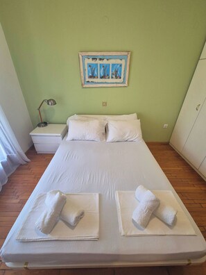 A neatly made bed with white linens and two towels, a nightstand with a lamp, and a painting on the wall. - GeoVilla 2 - Pefkochori Glarokavos (Pefkochori)