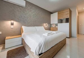 Ein modernes Schlafzimmer mit einem hölzernen Bett, Nachttischen, einem Einbauschrank und Wandleuchten.