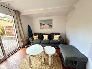 A living room with a grey sofa, two white side tables, a woven rug, and a bench. - Maison Piranga by Agence Bru - 731672 (Lacanau)